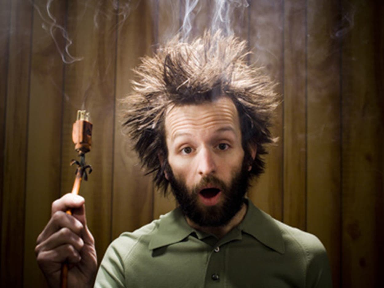 Man with hair standing on end holding a smoking plug